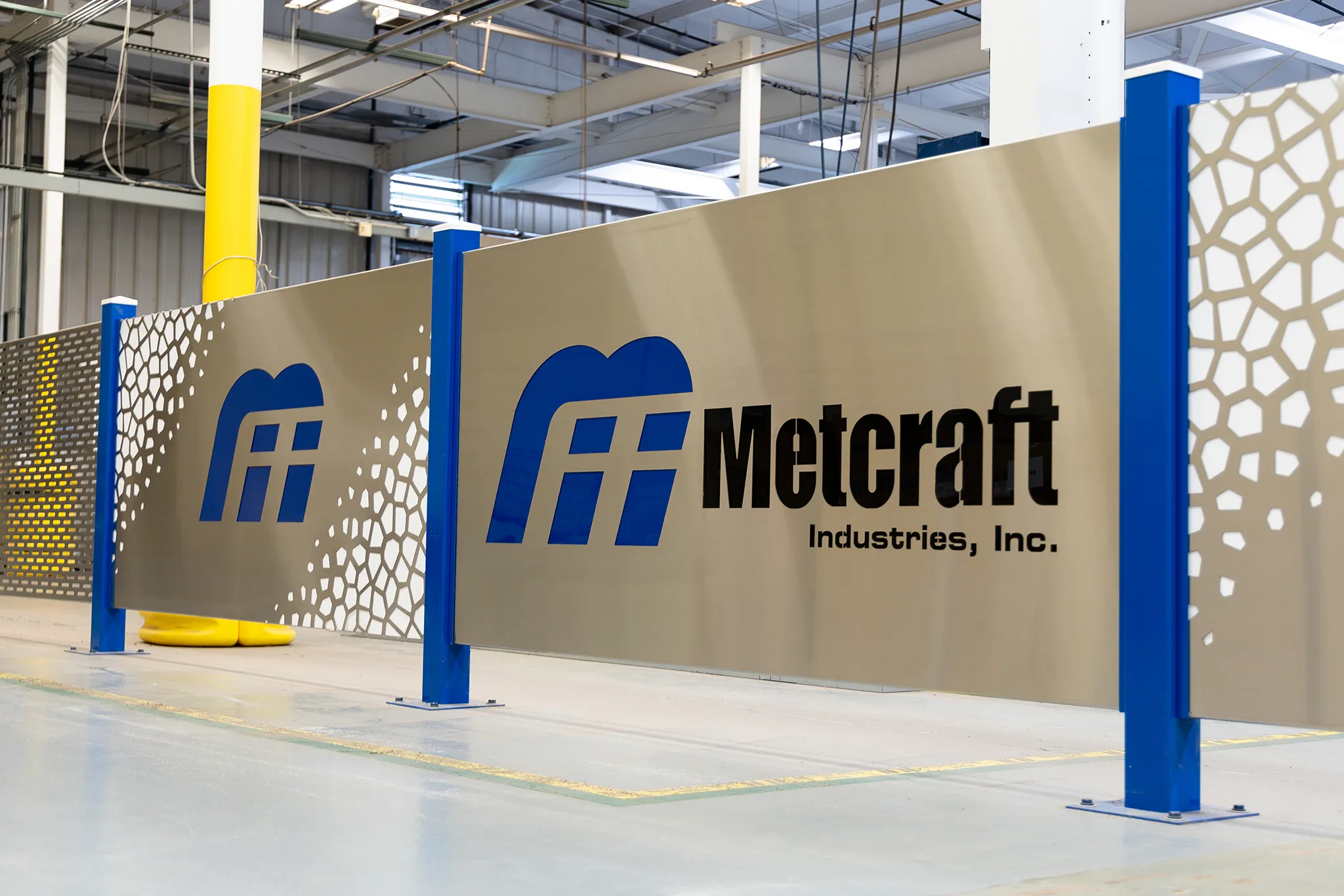 The Metcraft Industries logo on a shiny metal dividing wall.